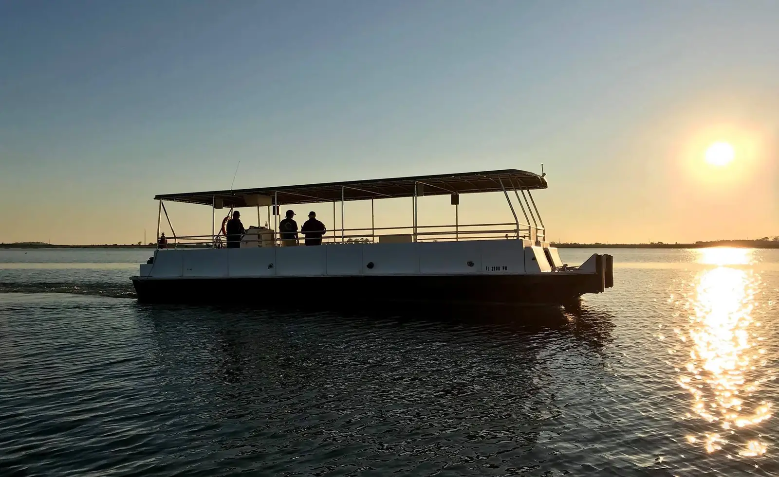 Our covered tour boat on calm water at sunset