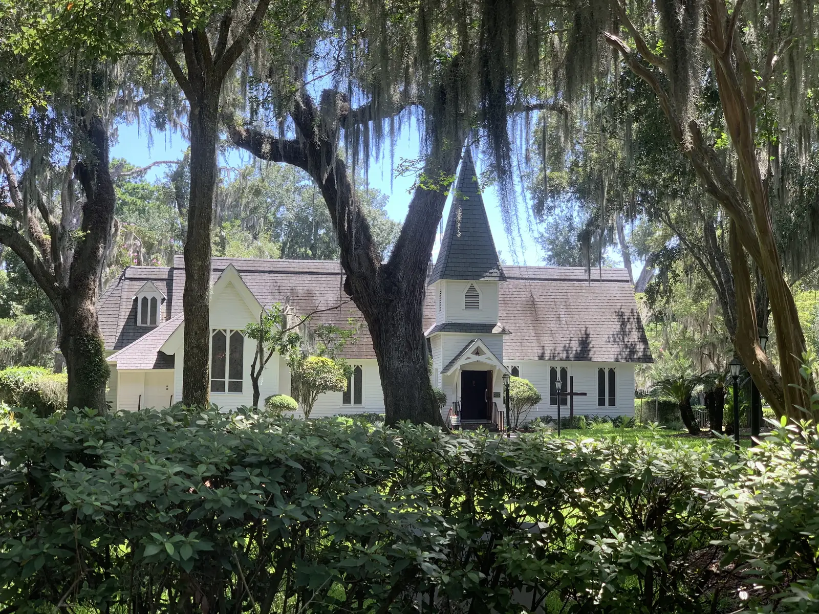 A historic white church framed by live oaks and Spanish moss