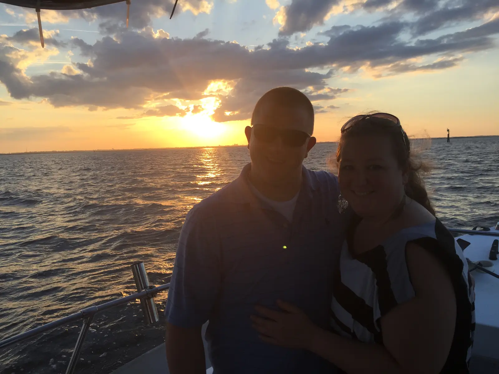 A couple smiling on deck during a sunset cruise