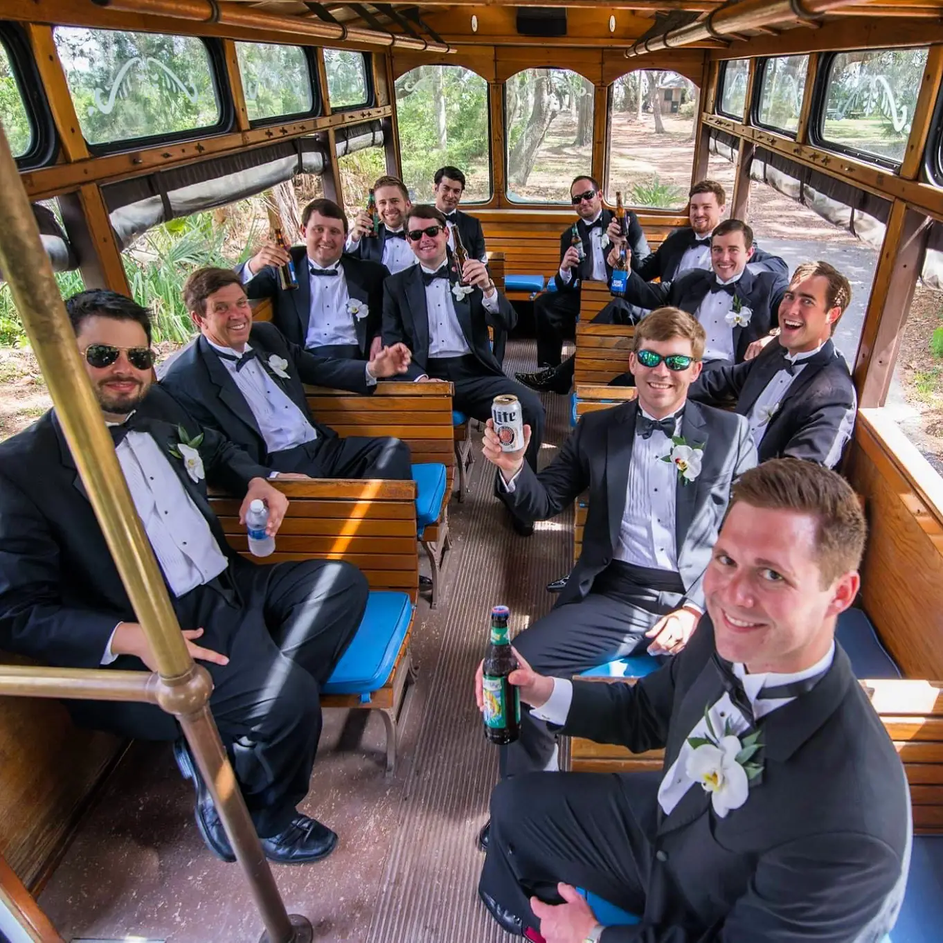 Groomsmen in tuxedos riding in a trolley