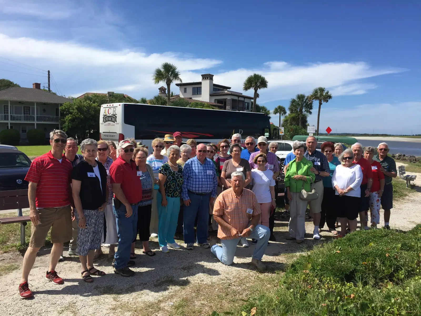 A large group posing in front of a trolley near the water