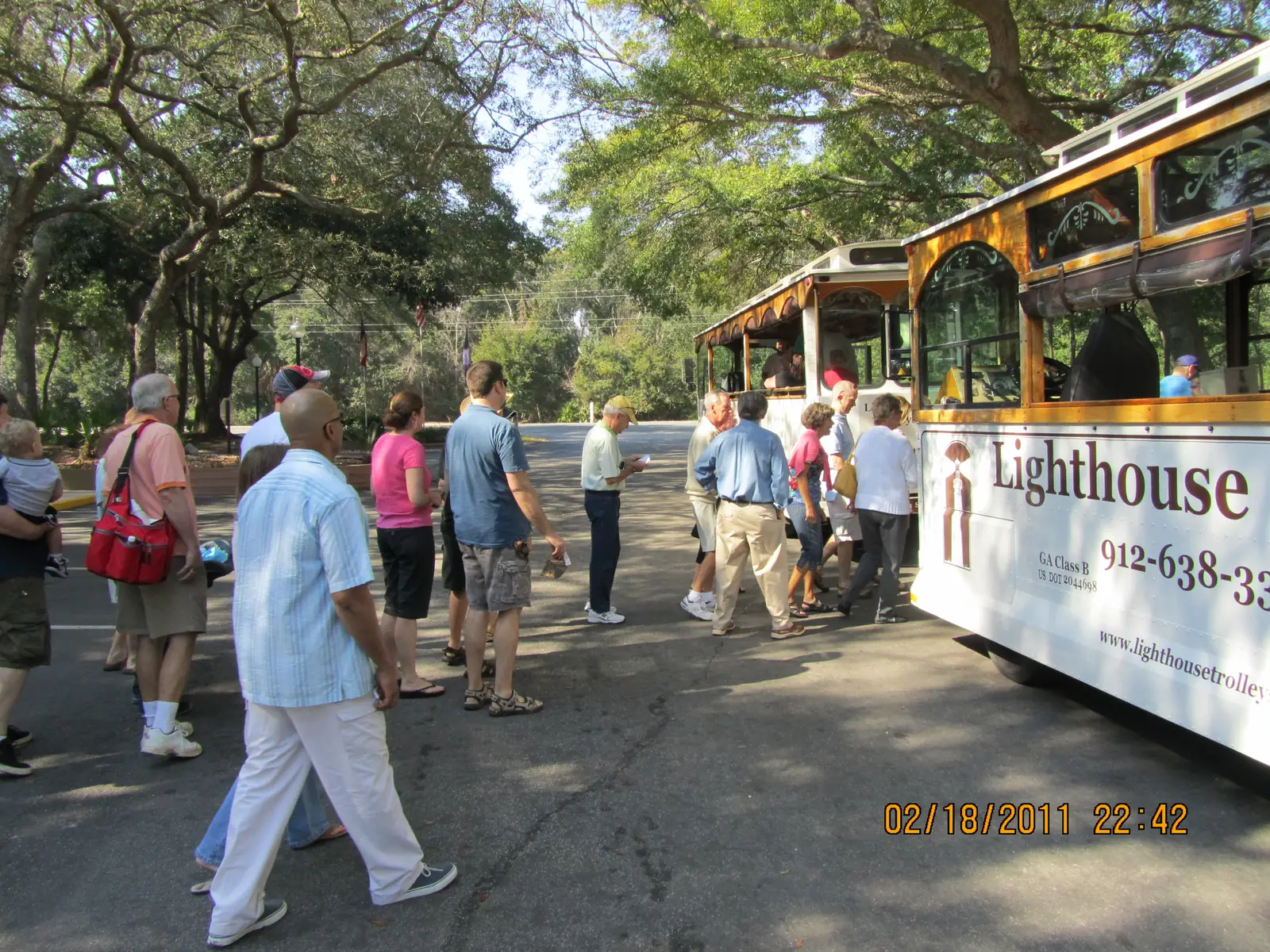 A tour group walking from the trolley under the oaks