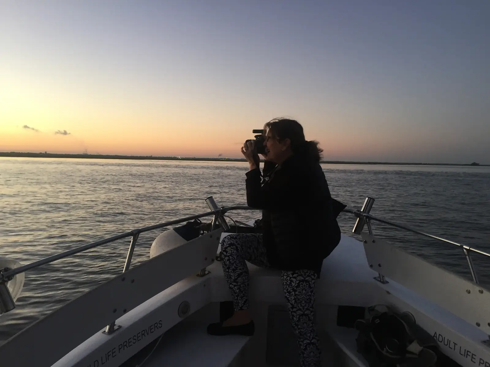 A guest photographing the sunset from the bow of the boat