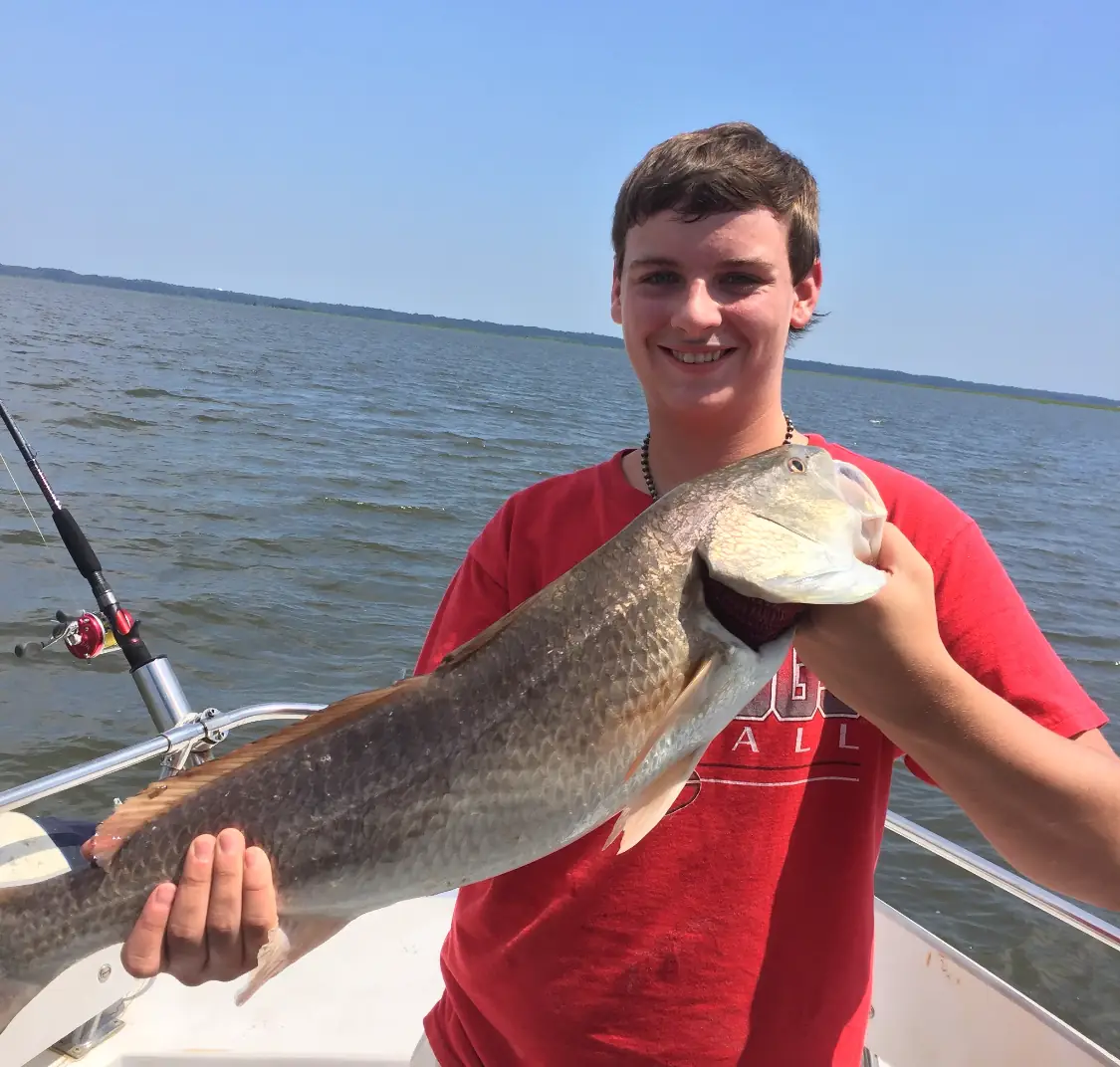A young angler proudly holding his redfish