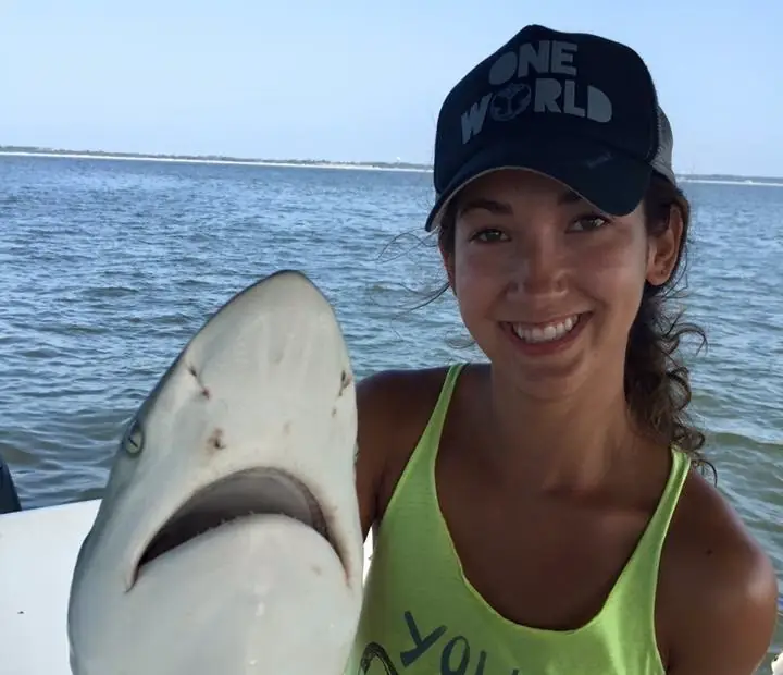 A smiling angler with a shark caught on a shark fishing charter