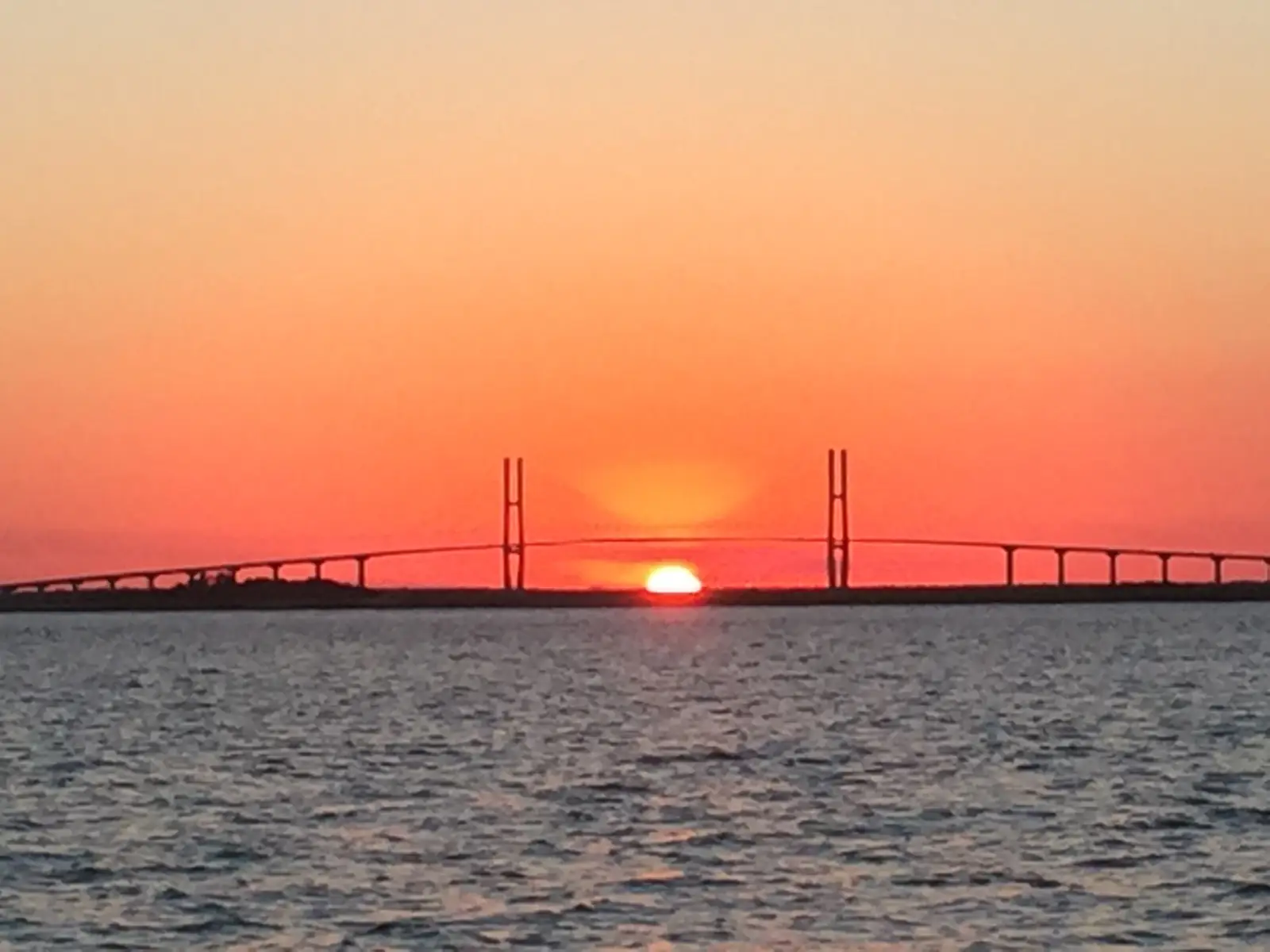 The sun setting behind the Sidney Lanier Bridge, seen from the water